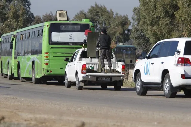 A United Nations vehicle and Syrian Army forces (C) escort buses carrying rebel fighters as they leave the district of Waer during a truce between the government and rebel fighters, in Homs, Syria December 9, 2015. (Photo by Omar Sanadiki/Reuters)