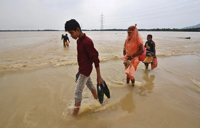 Villagers wade through a flooded road near a village in Hojai district, in the northeastern state of Assam, India, June 18, 2018. (Photo by Anuwar Hazarika/Reuters)