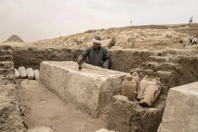 An Egyptian antiquities worker brushes a recently unearthed embalming bed at the site of the Step Pyramid of Djoser in Saqqara, 24 kilometers (15 miles) southwest of Cairo, Egypt, Saturday, May 27, 2023. (Photo by Amr Nabil/AP Photo)