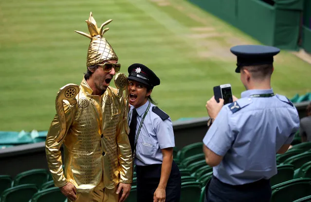 Wimbledon fan Chris Fava, dressed as the men’s singles trophy, poses for a photo with a London fire brigade officer on centre court on manic Monday, July 9, 2018. (Photo by Steven Paston/PA Wire)