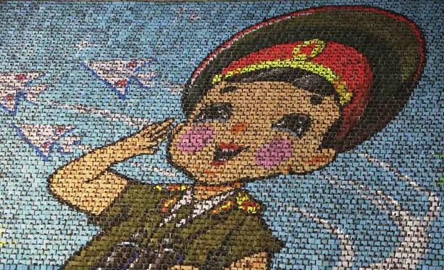 North Korean students use different coloured cardboards to form a picture of a child in uniform as a background during a mass gymnastic and artistic performance “Arirang”, in Pyongyang July 26, 2013, as part of celebrations ahead of the 60th anniversary of the signing of a truce in the 1950-1953 Korean War. The games are the world's biggest choreographed extravaganza, part circus act, part rhythmic gymnastics floor, with plenty of reverence for the late North Korean leader Kim Jong-il. (Photo by Jason Lee/Reuters)