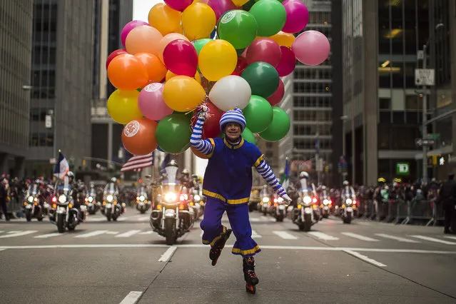 A performer carries balloons across Sixth Avenue during the Macy's Thanksgiving Day Parade, in New York, Thursday, November 24, 2016. (Photo by Andres Kudacki/AP Photo)