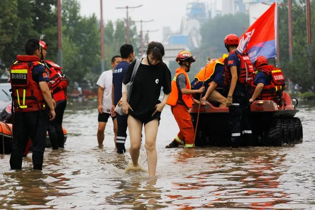 A woman wades through floodwaters next to rescue workers after remnants of Typhoon Doksuri brought rains and floods in Beijing, China on August 2, 2023. (Photo by Tingshu Wang/Reuters)