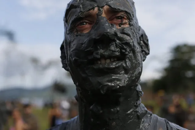 A mud covered reveler poses for the picture during the traditional “Bloco da Lama” or “Mud Block” carnival party, in Paraty, Brazil, Saturday, February 14, 2015. (Photo by Leo Correa/AP Photo)