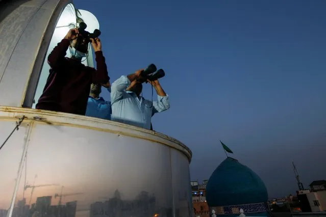 Men look through binoculars to view the moon ahead of Ramadan in the holy city of Najaf, Iraq, on April 12, 2021. (Photo by Alaa Al-Marjani/Reuters)