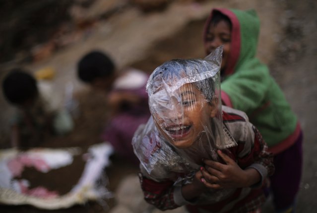 A boy with a plastic bag over his head plays with others outside their makeshift home in New Delhi February 11, 2015. (Photo by Adnan Abidi/Reuters)