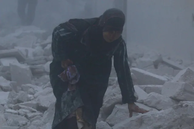 An injured woman walks at a site hit by an airstrike in the rebel-held al-Ansari neighbourhood of Aleppo, Syria December 7, 2016. (Photo by Abdalrhman Ismail/Reuters)