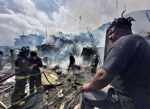 Firefighters work to put out a fire that affected dozens light material homes at two migrants' camps in Antofagasta, Chile, on May 13, 2021. (Photo by Glenn Arcos/AFP Photo)
