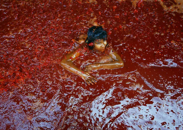 A child lies in a puddle of coloured water during “Huranga” at Dauji temple near the northern Indian city of Mathura, March 7, 2015. “Huranga” is a game played between men and women a day after Holi, the festival of colours, during which men drench women with liquid colours and women tear off the clothes of the men. (Photo by Anindito Mukherjee/Reuters)