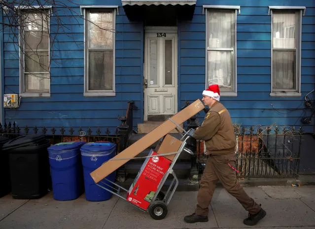 A UPS delivery driver delivers packages while wearing a Santa Claus hat in the Williamsburg neighborhood of Brooklyn, New York City, U.S., December 23, 2016. (Photo by Andrew Kelly/Reuters)