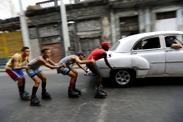 CUBA: Teenagers on roller skates hold on to each other as they are pulled by a vintage car to move along a street in Havana, Cuba March 19, 2016. (Photo by Ivan Alvarado/Reuters)