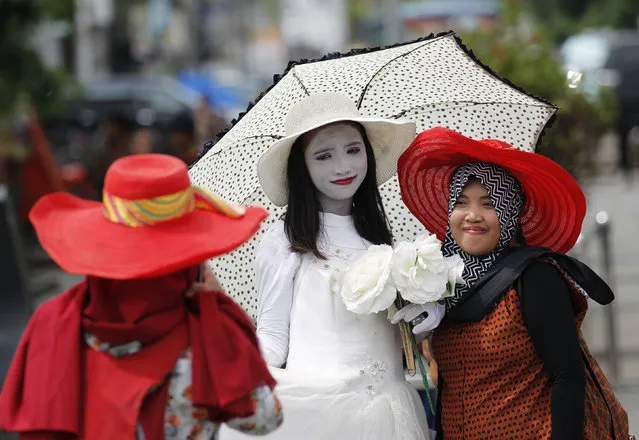 A woman has her picture taken with a street performer (C) in Kota Tua, or the Old Town, a popular tourist spot in Jakarta, Indonesia February 1, 2016. (Photo by Garry Lotulung/Reuters)