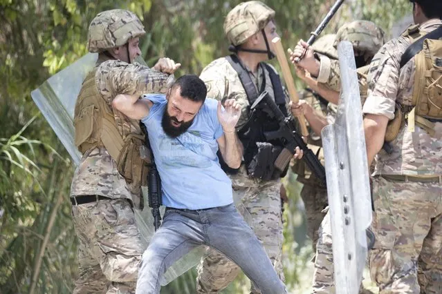 Lebanese soldiers scuffle with members of the Christian rightwing Lebanese Forces group, who attack buses carrying Syrian voters before heading to the embassy to vote, in the town of Zouk Mosbeh, north of Beirut, Lebanon, Thursday, May 20, 2021. (Photo by Hassan Ammar/AP Photo)