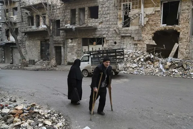 Residents walk beside damaged buildings in Aleppo December 31, 2014. Picture taken December 31, 2014. (Photo by Hamid Khatib/Reuters)