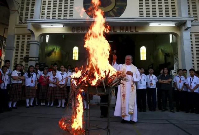 Father Jerry Habunal, a parish priest of Sta. Rita De Cascia, sprinkles holy water at burning dried palm leaves inside a Catholic school in Baclaran, Paranaque city, metro Manila, February 9, 2016. Filipinos in the predominantly Catholic nation will visit churches across the archipelago on Wednesday, the first day Lent, also known as Ash Wednesday, when priests apply ash from burnt palm leaves to a person's forehead. (Photo by Romeo Ranoco/Reuters)