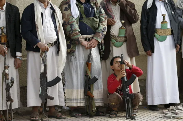 A boy holds his father's rifle as they attend a protest by followers of the Houthi movement against the Saudi-led air strikes in Sanaa April 5, 2015. (Photo by Khaled Abdullah/Reuters)