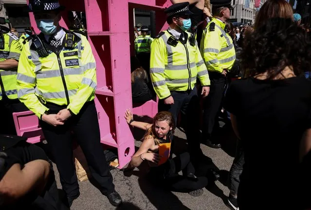 Police officers surround activists who fixed themselves to a structure during an Extinction Rebellion climate activists' protest, at Oxford Circus, in London, Britain on August 25, 2021. (Photo by Henry Nicholls/Reuters)