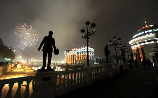 Silhouettes of sculptures are seen on a bridge, as fireworks explode over Vardar River during New Year's Eve celebration in Skopje, Macedonia, Wednesday, January 1, 2014. (Photo by Boris Grdanoski/AP Photo)