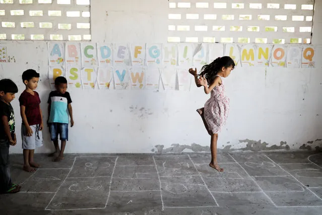 (L-R) Adriel, 6, Matheus 6, and Rian, 5, look at her classmate Michelly as they play during class at Sao Jose school in Morro Do Veridiano, Belagua Municipality, Maranhao state, Brazil, October 10, 2018. Picture taken October 10, 2018. According to the 2015 National Household Sample Survey (Pnad), 2.8 million children and adolescents aged 4 to 17 are out of school. More than half (53 percent) come from households whose income per capita does not exceed half the minimum wage, a value of 477 reais (~$123 USD). While Brazil is in the top ten economies in the world, there are still millions of people in the northeast of the country who are in extreme poverty. (Photo by Nacho Doce/Reuters)