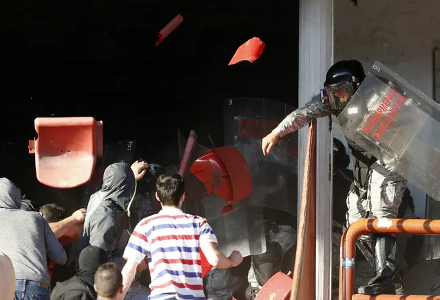 A Serbian riot police officer clashes with Red Star fans during a Serbian National soccer league derby match between Red Star and Partizan, in Belgrade, Serbia, Saturday, April 25, 2015. (Photo by Darko Vojinovic/AP Photo)