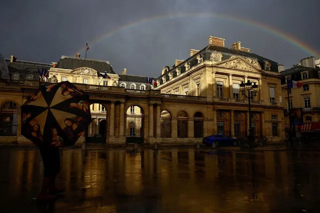 A woman holds an umbrella depicting the Mona Lisa by Leonardo Da Vinci as she looks a the rainbow near the Conseil d'Etat, France's highest administrative court in Paris, France on November 10, 2023. (Photo by Gonzalo Fuentes/Reuters)
