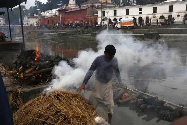 A hindu priest lights the funeral pyre of a victim of Saturday's earthquake, at the Pashupatinath temple, on the banks of Bagmati river, in Kathmandu, Nepal, Monday, April 27, 2015. (Photo by Manish Swarup/AP Photo)