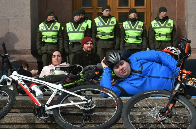 Bicyclists take part in the die-in action in front of the city hall of the Ukrainian capital Kiev on March 14, 2019 to ask modern infrastructure for safe cycling traffic. The protesters demand modern infrastructure for safe cycling traffic in the city and severely punish drivers who ignore cyclists on the road. (Photo by Sergei Supinsky/AFP Photo)