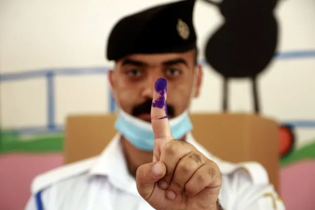 An Iraqi federal policeman ​displays his ink-stained finger at a polling center during the early voting for security forces ahead of Sunday's parliamentary election in Baghdad, Iraq, Friday, October 8, 2021. (Photo by Hadi Mizban/AP Photo)