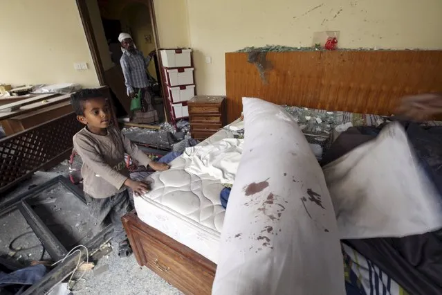 A boy walks in a room as he helps to move furniture from a house damaged after an air strike by a Saudi-led coalition struck a nearby missile base, in Yemen's capital Sanaa April 27, 2015. (Photo by Mohamed al-Sayaghi/Reuters)