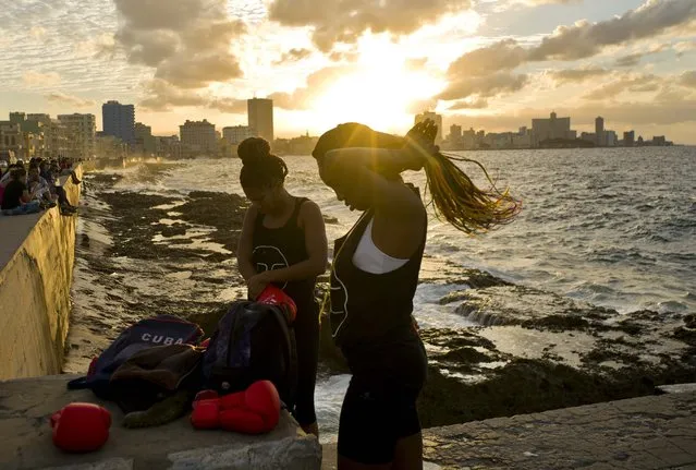 In this January 30, 2017 photo, boxers Idamerys Moreno, left, and Legnis Cala, get ready for a photo session on Havana's Malecon, in Cuba. Moreno trains at least two hours a day after she gets off work, completing a routine that includes running several miles, lifting weights, hitting a punching bag and sparring with both women and men. (Photo by Ramon Espinosa/AP Photo)