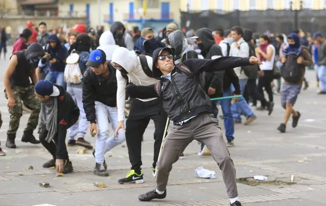 A demonstrator throws a stone during clashes against police on Labor Day in Bogota, Colombia May 1, 2015. (Photo by Jose Miguel Gomez/Reuters)