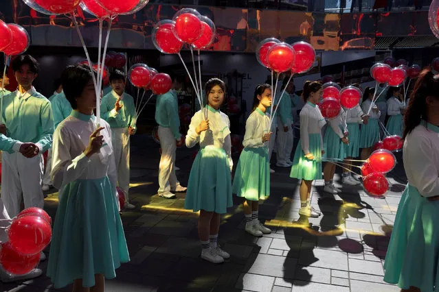 Performers carry red balloons during the filming of a Chinese Communist Party propaganda video in an upscale shopping district in the Sanlitun area in Beijing, China, October 19, 2021. (Photo by Thomas Peter/Reuters)