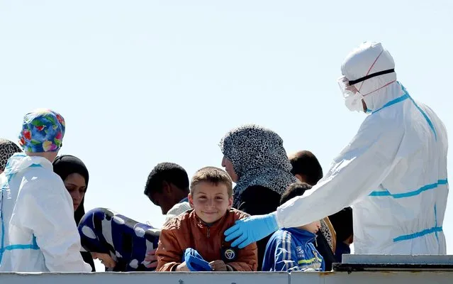 An Italian naval officer interacts with a child amongst rescued migrants onboard the Italian Navy vessel Bettica as they arrive in the Sicilian harbour of Augusta on April 22, 2015. (Photo by Alberto Pizzoli/AFP Photo)