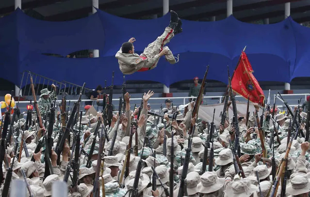 A member of the Bolivarian Militia is thrown into the air by his comrades during their tenth anniversary celebration in Caracas, Venezuela, Saturday, April 13, 2019. Officially known as the Venezuelan National Bolivarian Militia, it is a branch of the National Armed Forces of Venezuela created by the late President Hugo Chavez and today it is made up of over 2 million men and women. (Photo by Ariana Cubillos/AP Photo)