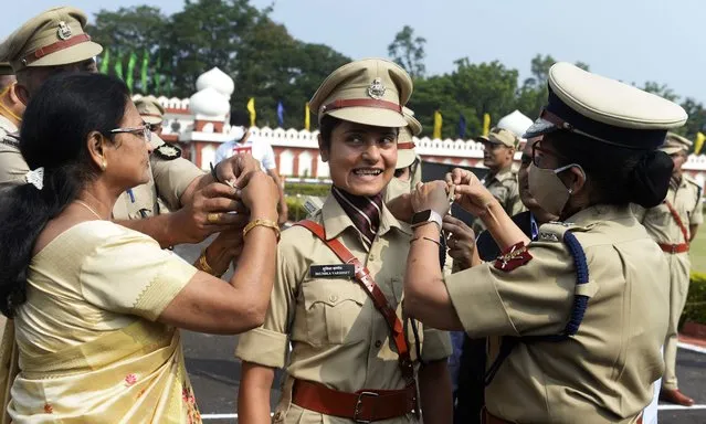 A member of the Central Industrial Security Force (CISF) reacts as her mother (L) places a badge with stars on the uniform during the 34th batch assistant commandants pipping ceremony at the National Industrial Security Academy (NISA) in Hyderabad on October 29, 2021. (Photo by Noah Seelam/AFP Photo)
