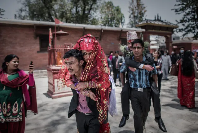 Nepalese couple Anita Thapa, 22, (C) and Sagar KC, 24, (back) are carried by their respective brothers towards their bus during their wedding which was postponed after the 7.8 magnitude earthquake which struck the Himalayan nation on April 25, in Mahadevisthan temple in Kathmandu on May 3, 2015. (Photo by Philippe Lopez/AFP Photo)