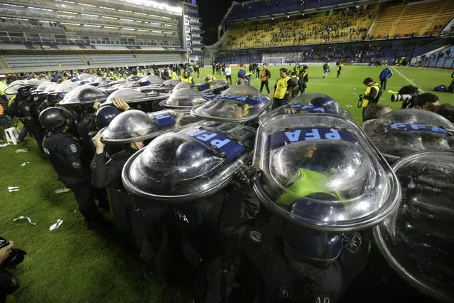 Riot police hold up their shields to make a corridor for River Plate players exit the stadium after their  Copa Libertadores soccer match with Boca Juniors was suspended after the first half in Buenos Aires, Argentina, Friday, May 15, 2015. Police are investigating after the high-profile match was stopped when visiting players were sprayed by fans with an eye irritant believed to be pepper spray or mace. (Photo by Victor R. Caivano/AP Photo)