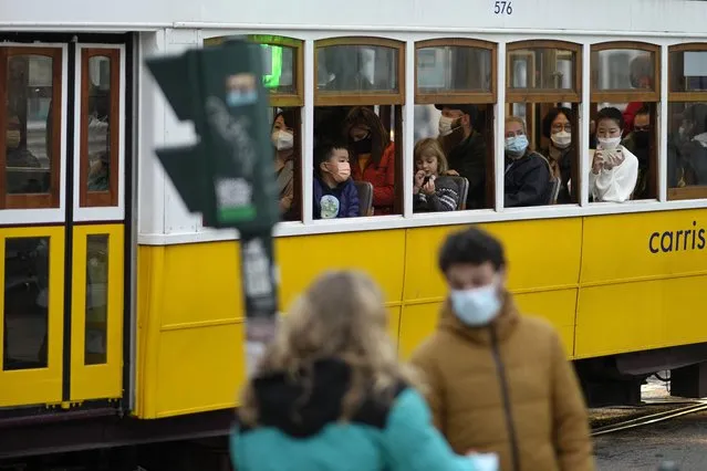 People wearing face masks ride a tram in Lisbon, Wednesday, December 22, 2021. Despite vaccination rates that make other governments envious, Spain and Iberian neighbor Portugal are facing the hard truth that, with the new omicron variant running rampant, these winter holidays won't be a time of unrestrained joy. Portugal announced Tuesday a slew of new restrictions over Christmas and the New Year. (Photo by Armando Franca/AP Photo)