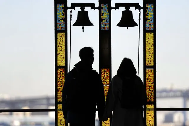 A man and a woman ring the bells Tuesday, December 28, 2021, in Yokohama, near Tokyo. (Photo by Eugene Hoshiko/AP Photo)
