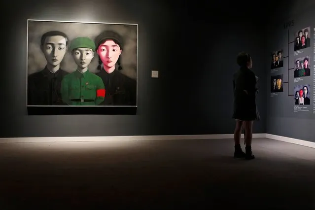 A woman reads the introduction of the painting “Bloodline: Big Family No.3” by Chinese artist Zhang Xiaogang during a preview for the Sotheby's Modern and Contemporary Asian Art Evening Sale in Hong Kong Wednesday, April 2, 2014. The painting is expected to fetch HK$ 65–80 million (US$ 8.3–10.3 million). (Photo by Kin Cheung/AP Photo)