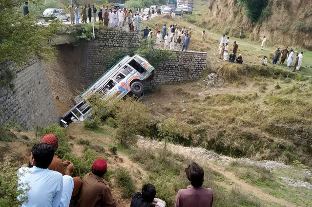Local residents check the wreckage of a passenger bus after it fell into a ravine in Taxila Haripur Road in Hattar Industrial Estate Dohrian Bridge, Pakistan, 05 April 2014. At least three people were killed and several others injured in the bus accident. Fatal traffic accidents are common in Pakistan with most of them said to be caused by reckless driving and poor road conditions. (Photo by Ultan Dogar/EPA)
