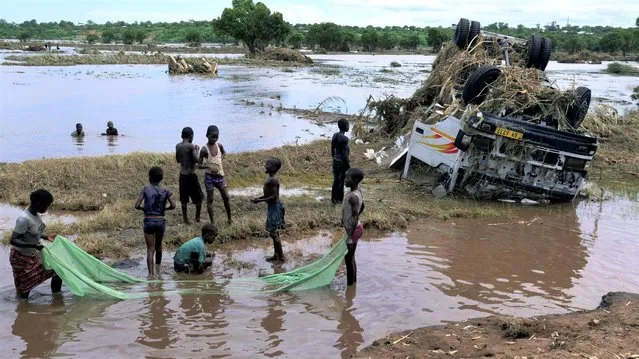 Children use a mosquito net to catch fish near a wreck, washed away during tropical storm Ana on the flooded Shire river, an outlet of Lake Malawi at Thabwa village, in Chikwawa district, southern Malawi, January 26, 2022. (Photo by Eldson Chagara/Reuters)