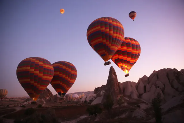 Hot air balloons glide over Goreme district during early morning at the historical Cappadocia region, located in Central Anatolia's Nevsehir province, Turkey on September 23, 2019. Cappadocia is preserved as a UNESCO World Heritage site and is famous for its chimney rocks, hot air balloon trips, underground cities and boutique hotels carved into rocks. The Cappadocia region is the most popular location in the world for hot air ballooning. (Photo by Behcet Alkan/Anadolu Agency via Getty Images)