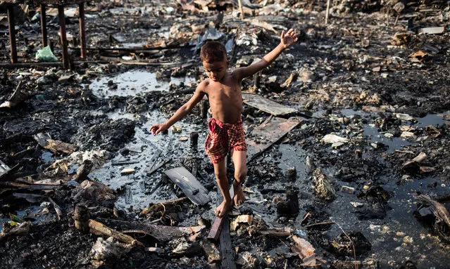 A boy walks through debris after fire razed the Mirpur slum in Dhaka, Bangladesh on August 20, 2019. (Photo by Md Rakibul Hasan/Pacific Press via ZUMA Wire/Rex Features/Shutterstock)