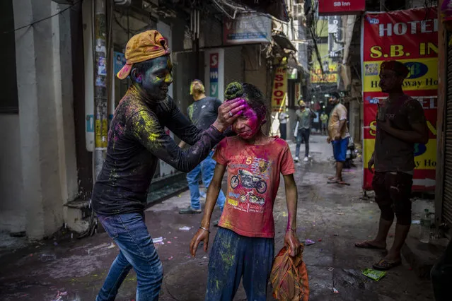 A boy smears the face of a young Sikh boy with colored powder on Holi, the Hindu festival of colors, in New Delhi, India, Friday, March 18, 2022. (Photo by Altaf Qadri/AP Photo)