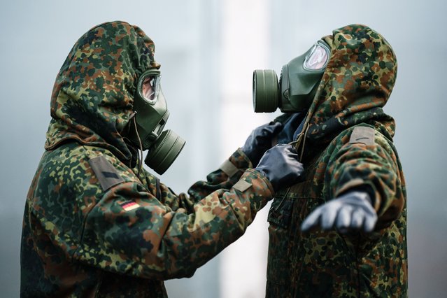 Soldiers with gas masks remove clothes on the occasion of a NBC demonstration during a visit of German Defense Minister Pistorius to the Joint Support and Enabling Service (Streitkraeftebasis) of the German Armed Forces “Bundeswehr” in Mahlwinkel, near Magdeburg, Germany, 16 March 2023. Pistorius attended various exercises of troop units of the German Armed Forces Bundeswehr’s Joint Support and Enabling Service on a former aviation site at Mahlwinkel. (Photo by Clemens Bilan/EPA)