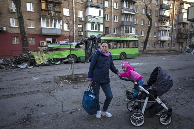 Lena Danilova, 39, walks with her daughter Kira, 2, near her house in Podolskyi neighborhood, Kyiv, Ukraine, Friday, March 25, 2022. “I decided to stay, but since it continues so long, I don't think its safe any more, so I am working on leaving soon with my other two sons”, said Lena to The Associated Press. (Photo by Rodrigo Abd/AP Photo)