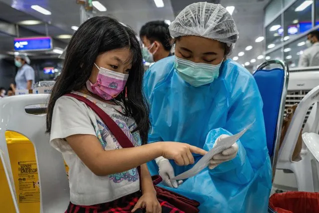 A young girl selects a colorful sticker prior to receiving the Pfizer-BioNTech COVID-19 vaccine. Children aged 5-11 receive the Pfizer-BioNTech COVID-19 vaccine (Comirnaty) at Bang Sue Central Station in Bangkok on February 20, 2022. (Photo by Matt Hunt/SOPA Images/Rex Features/Shutterstock)