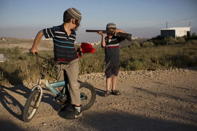 In this Wednesday, May 18, 2016 photo, Jewish settler boys play with toy guns in Amona, an unauthorized Israeli outpost in the West Bank, east of the Palestinian town of Ramallah. It is the largest of about 100 outposts in the West Bank which were built without permission but generally tolerated by the government. Under an Israeli Supreme Court order, the government must tear down the outpost by the end of 2016. (Photo by Oded Balilty/AP Photo)
