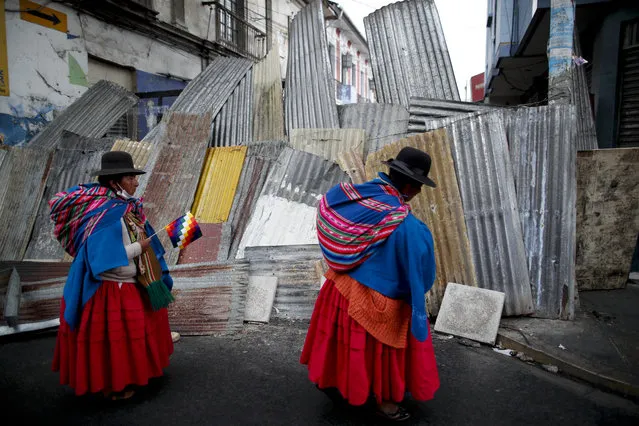 Supporters of former President Evo Morales stand at a barricaded stretch leading to the presidential palace during a march in La Paz, Bolivia, Thursday, November 14, 2019. Morales resigned and flew to Mexico under military pressure following massive nationwide protests over alleged fraud in an election last month in which he claimed to have won a fourth term in office. (Photo by Natacha Pisarenko/AP Photo)